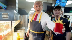 Donald J. Trump wearing an apron while dispensing french fries at a McDonald's fast food restaurant in Pennsylvania as part of a campaign stunt on Sunday, October 20, 2024. Photo by Doug Mills/AP.